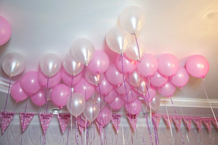 Bild zeigt an der Decke schwebende Luftballons in weiss und rosa.
