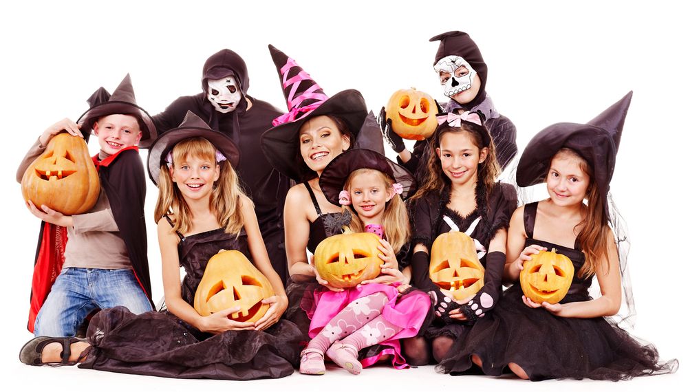 Auf dem Bild ist eine Gruppe Mädchen und Jungen in unterschiedlichen Halloweenverkleidungen zu sehen, die gruselige Kürbisse halten