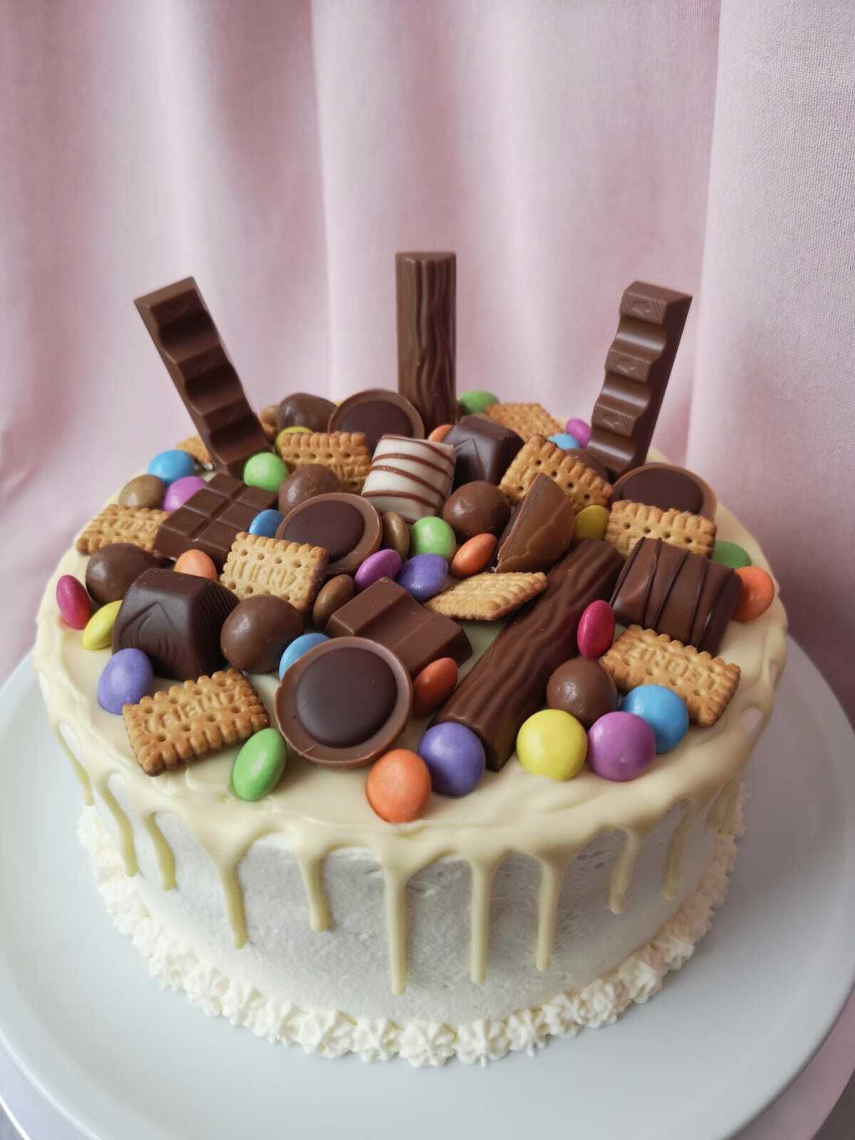 Auf dem Bild ist eine Geburtstagstorte zu sehen dekoriert mit allerlei Keksen, bunten Schokokugeln, Pralinen und Kinderschokoladeriegeln.